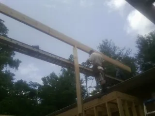Carpenter setting a ridge beam over a new addition frame — Ice Dam Removal by Roofing Brothers in Swanlake