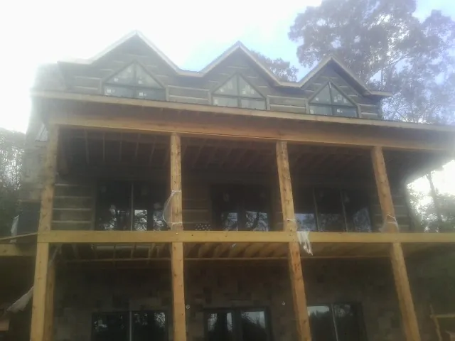 Dormers and porch framing on a large log home under construction — Roof Coating work by our crew in Swanlake