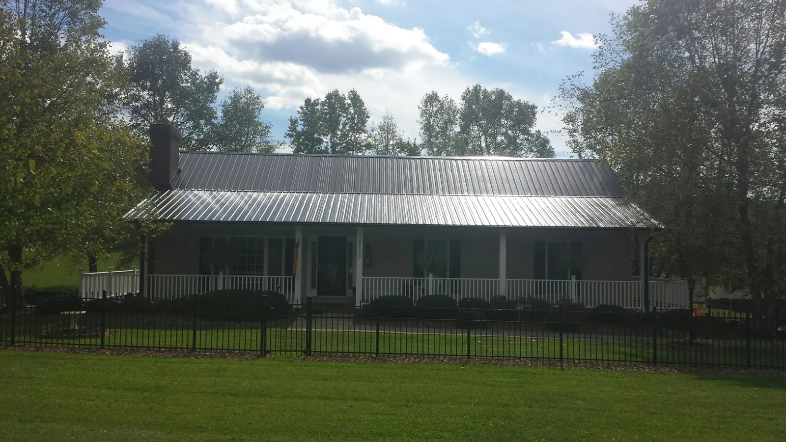 Gray metal roof on a brick ranch with a full width front porch — Gutter Guard Installation work by our crew in Swanlake