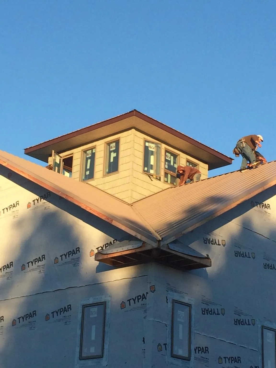 Roofers working around a rooftop cupola on a new metal roof at sunset — Roof Waterproofing in Swanlake by Roofing Brothers